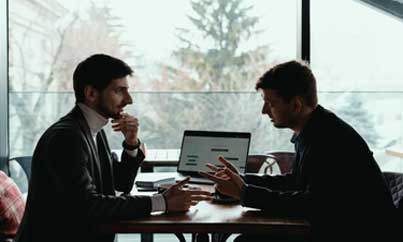 Two men in professional attire discussing work.