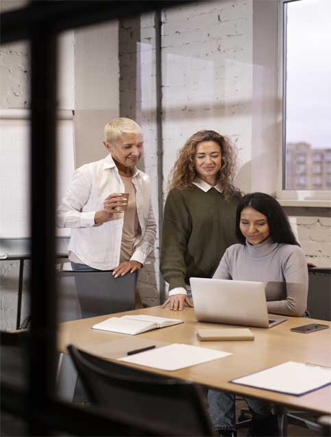 A group of people happily talking around a laptop, suggesting a collaborative learning or work environment.